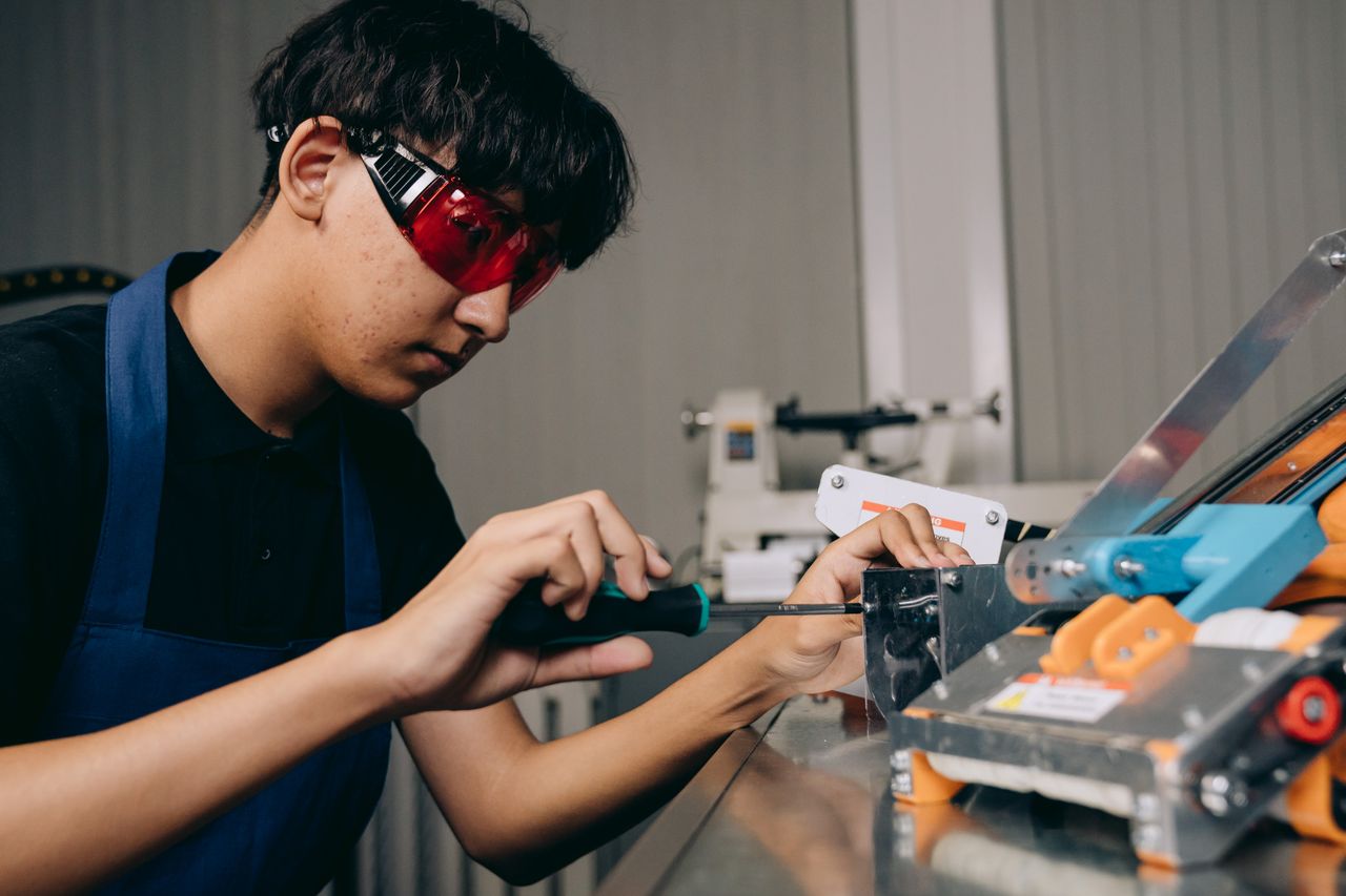 Junge Person arbeitet mit Schutzbrille an technischen Komponenten
