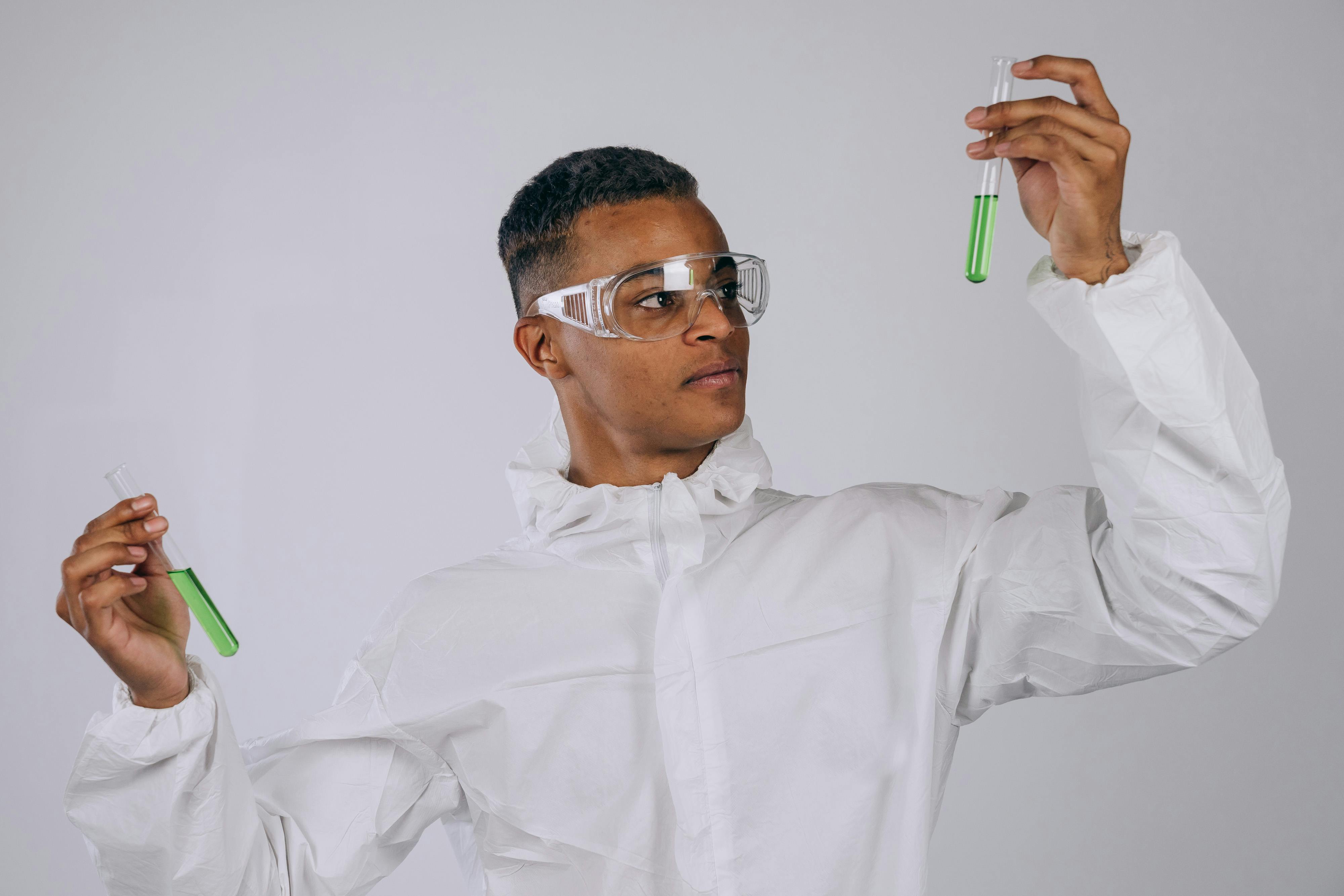 Scientist in PPE examining test tubes in a lab