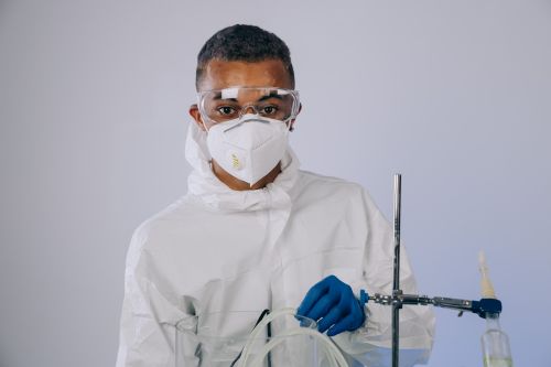 Free A scientist in a protective suit and mask works in a laboratory setting, demonstrating safety protocols. Stock Photo