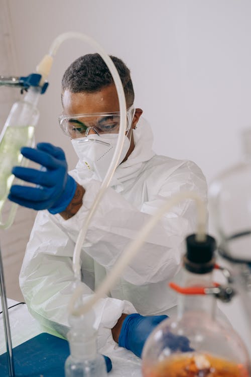 Free Person in White Medical Scrub Holding Clear Glass Bottle Stock Photo