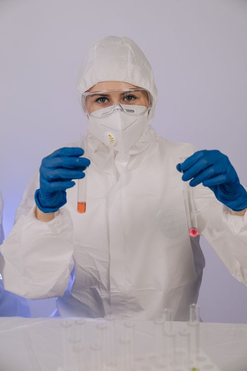Free Scientist wearing protective gear conducts tests with colorful liquids in a lab. Stock Photo