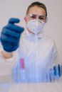 A Woman Wearing Safety Glasses and Face Mask Holding a Test Tube