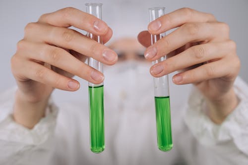 Hands Holding Test Tubes with Green Chemical