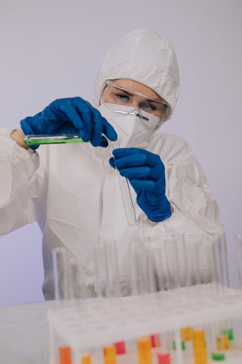 A Person in Personal Protective Equipment Near Test Tubes