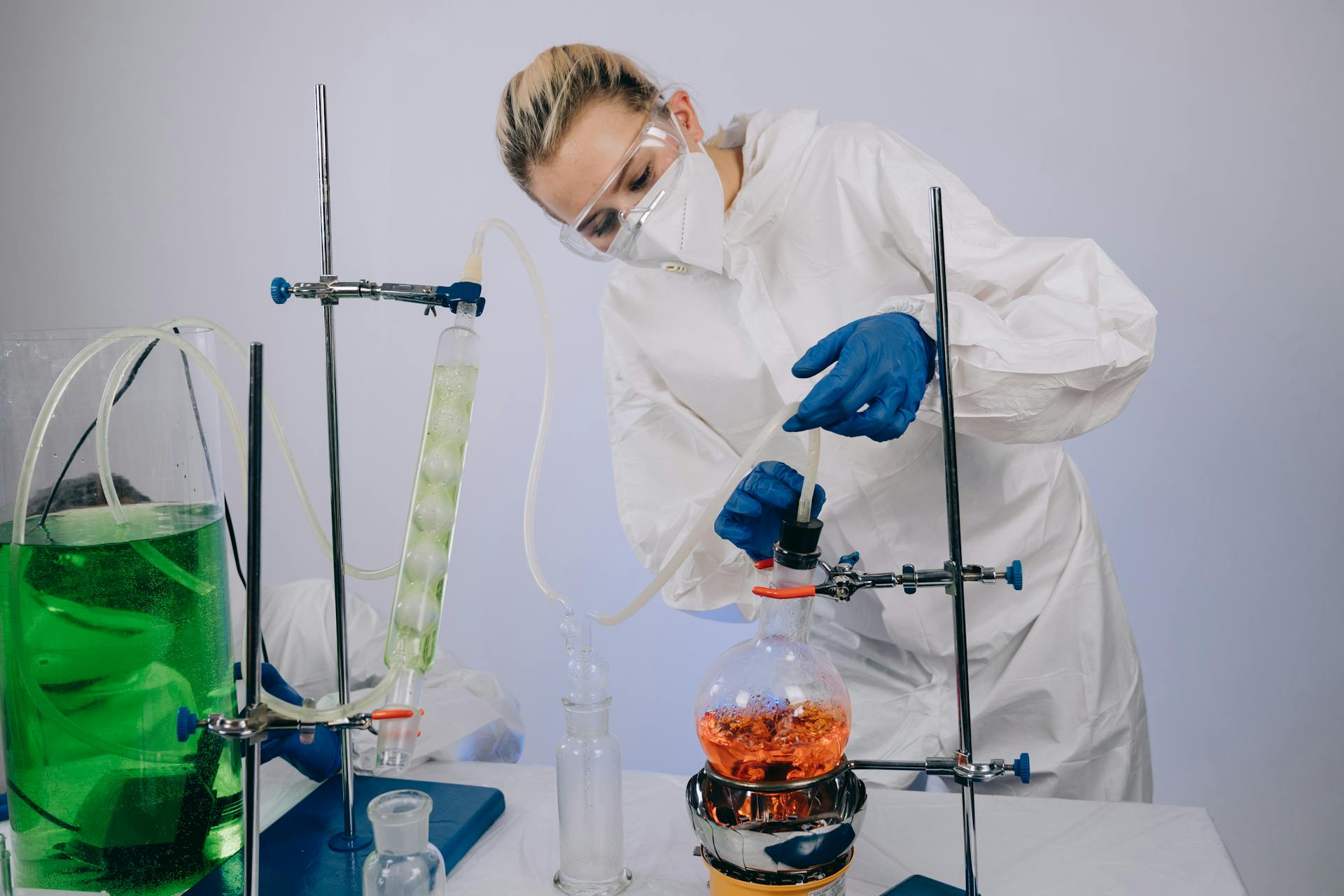 A scientist performs a chemical experiment in a laboratory wearing full protective gear, illustrating modern science.