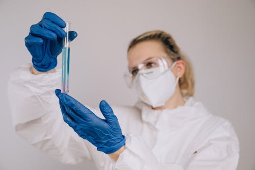 Scientist in PPE looking at a Test Tube 