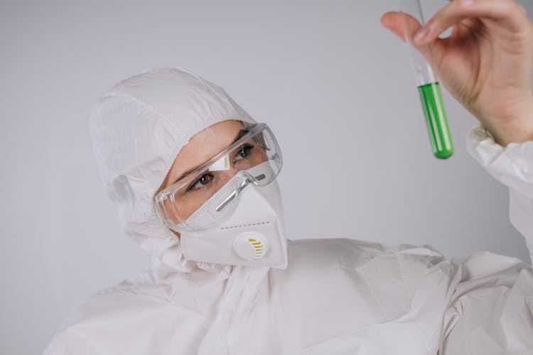 Person With Facemask And Goggles Looking At A Test Tube