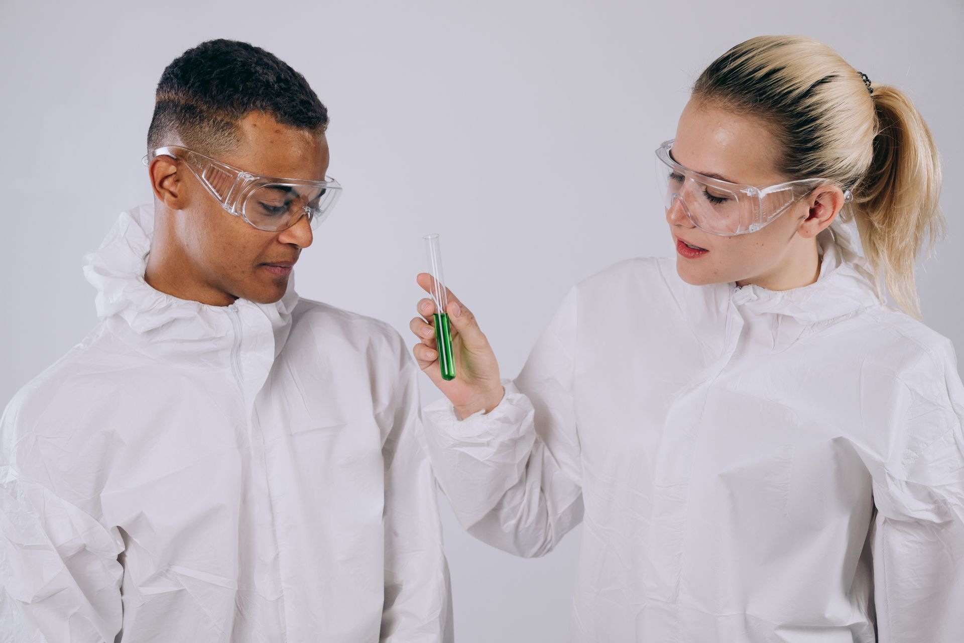Researchers in protective gear analyze a test tube sample in a laboratory setting, showcasing teamwork and scientific exploration.