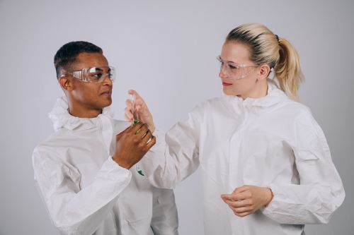 Free Two scientists in protective gear working together with a test tube in a laboratory setting. Stock Photo