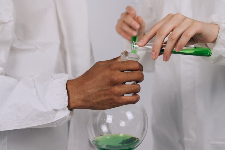 Scientists Pouring Chemical In A Beaker