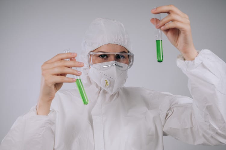 Chemist In Complete PPE Holding Test Tubes 