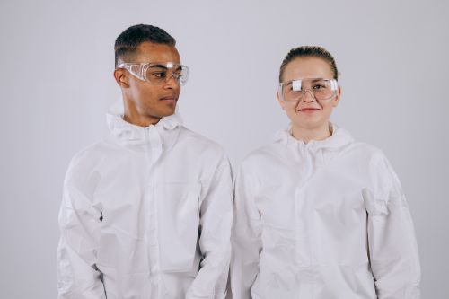 Free Two scientists in protective suits and goggles, focused on their work, illustrating modern laboratory safety. Stock Photo