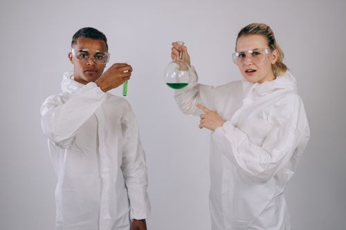 Free Two scientists in protective gear conducting a chemical experiment indoors. Stock Photo