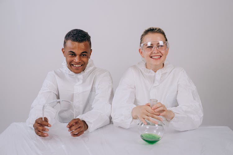 Smiling Man And Woman Holding A Beaker And Goggles