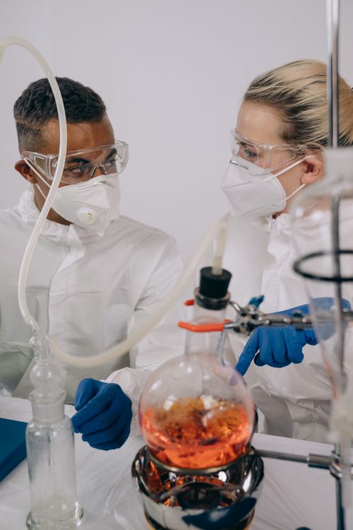 Free Two scientists in protective gear conduct a chemical experiment in a lab setting, ensuring safety protocols. Stock Photo