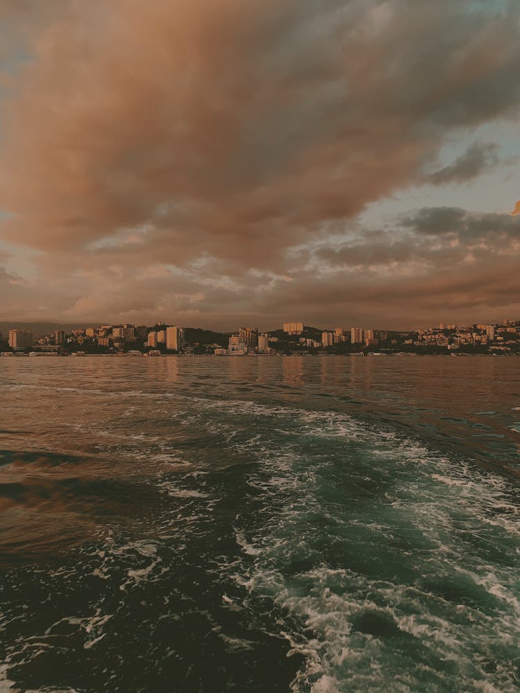 Boat Trail On The Sea And City At Dusk 