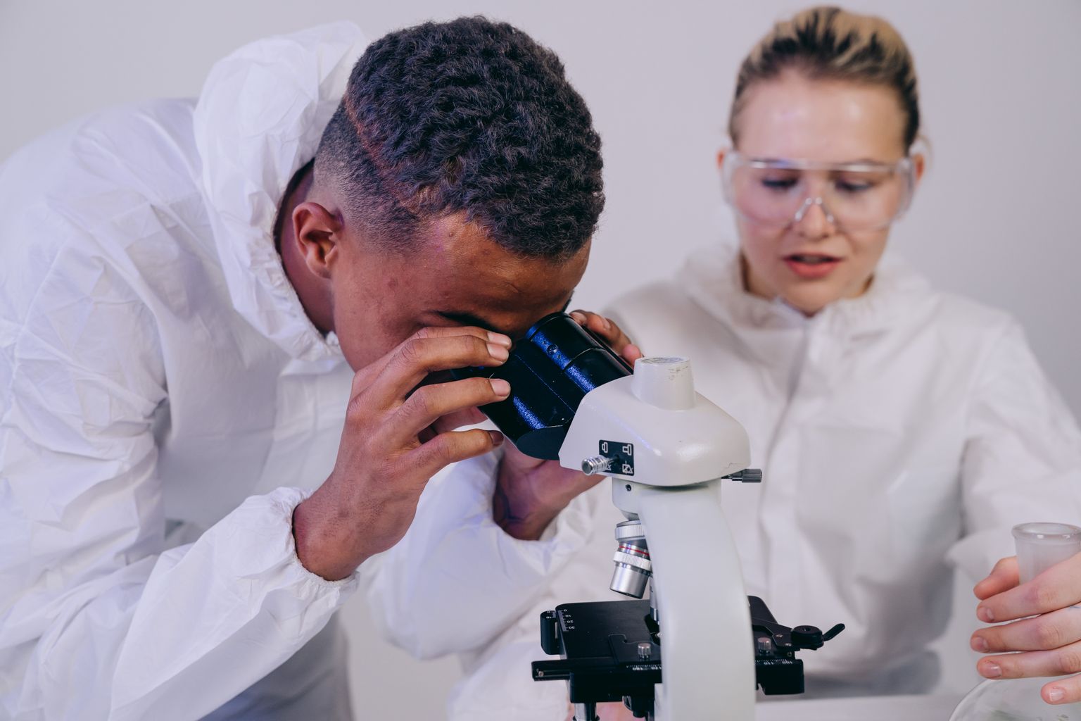 Two laboratory scientists working together at a microscope