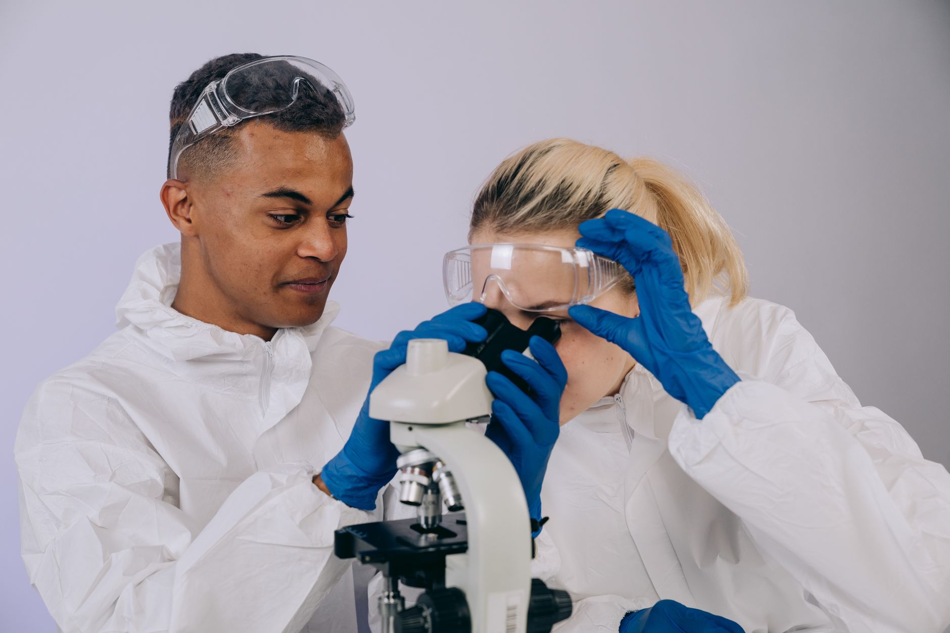 Two scientists in lab coats using a microscope in a laboratory setting.