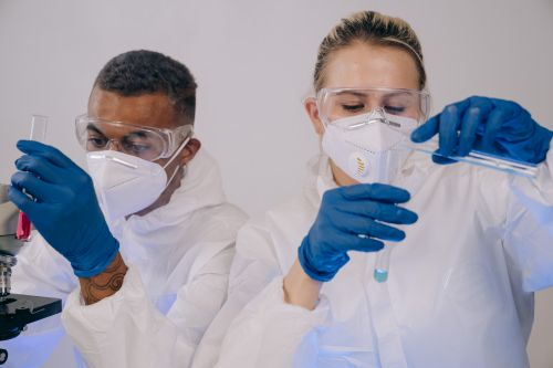 Free Two laboratory scientists in protective gear conducting experiments with test tubes. Stock Photo