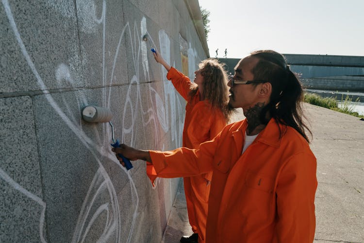 A Man And Woman Painting A Wall