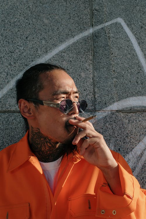 Man in Orange Shirt Smoking Cigarette