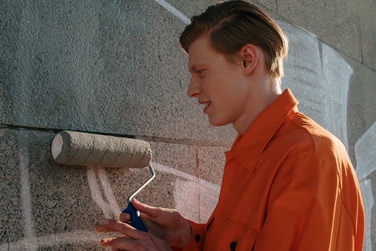 An Inmate Painting Over A Gray Wall