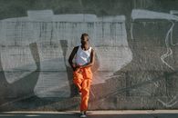 Man in Orange Pants and White Shirt Standing on Gray Concrete Floor