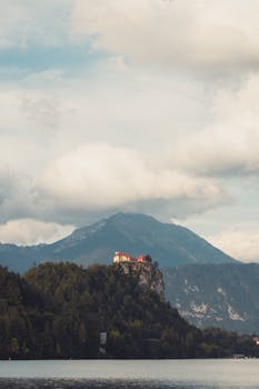 Picturesque view of Bled Castle on a hilltop with mountains and lake in Slovenia.