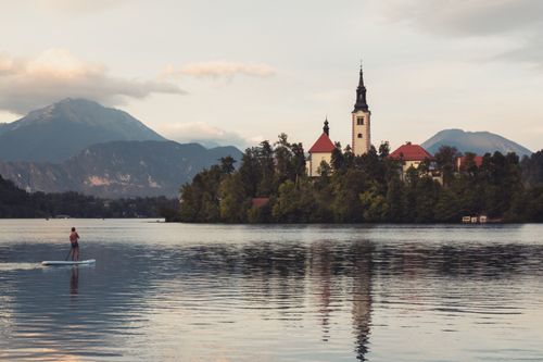 Free Tranquil sunset at Lake Bled with a paddleboarder and church island. Stock Photo