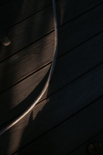 Artistic composition of light and shadow on textured wooden decking planks.