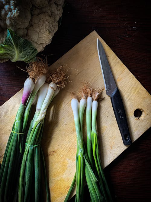 Close-Up Shot of a Knife and Vegetables on a Wooden Chopping Board