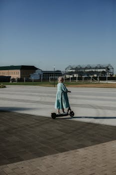 Woman on scooter in urban park setting, showcasing modern outdoor lifestyle.