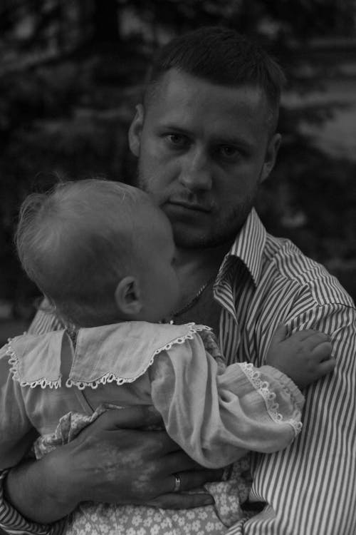 Grayscale Photo of a Man Carrying a Baby 