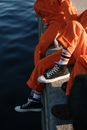 Person in Orange Pants and Black and White Nike Sneakers Sitting on Gray Concrete Surface