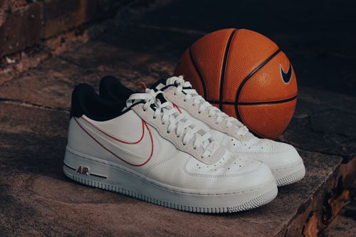 Free Stylish white sneakers paired with a Nike basketball on a rustic stone background. Stock Photo