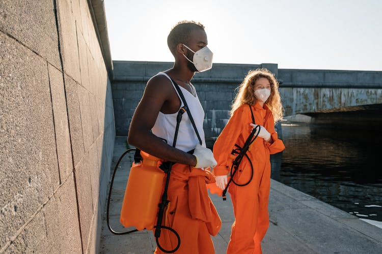 Cleaners In Orange Uniform Standing Near The River