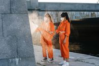 Woman in Orange Robe Standing on Gray Concrete Floor