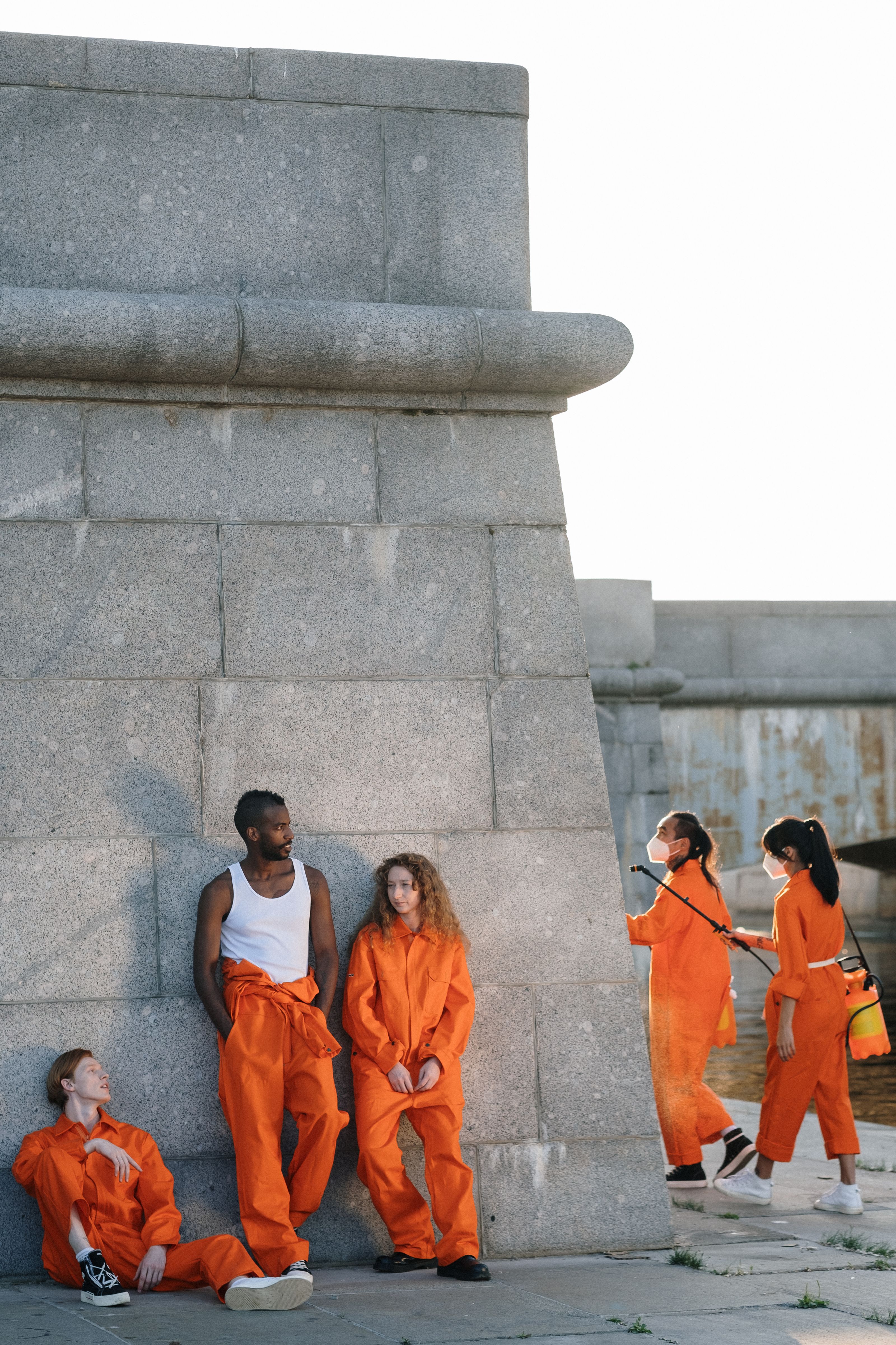 Grupo de indivíduos diversos em uniformes laranja participando de serviço comunitário ao ar livre.