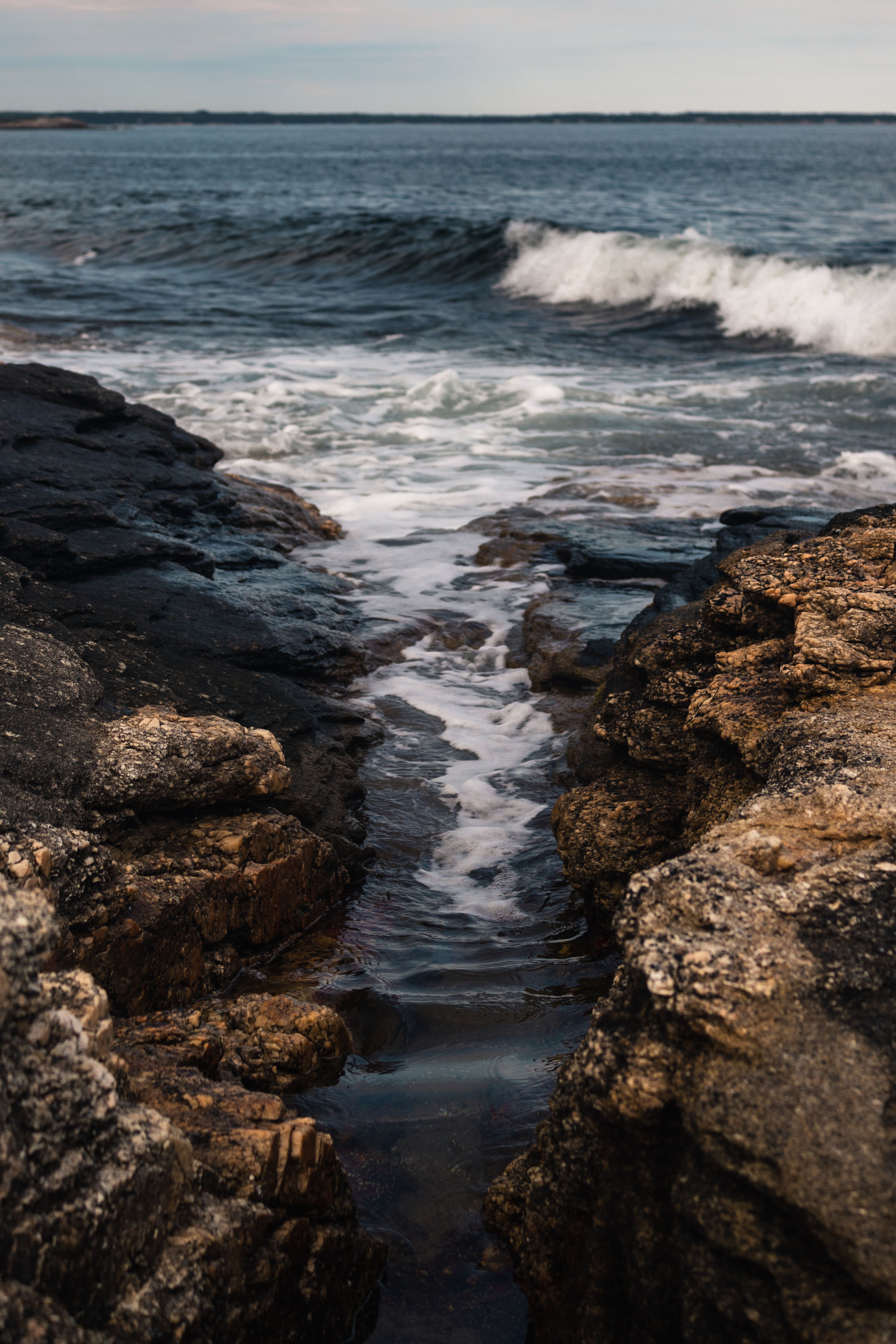 Captivating view of waves meeting rocky shoreline at sunrise, showcasing nature's dynamic beauty.