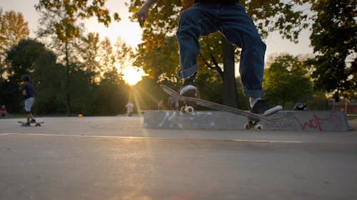 A Person in Blue Denim Jeans and Black Shoes Doing Stunt on a Skateboard
