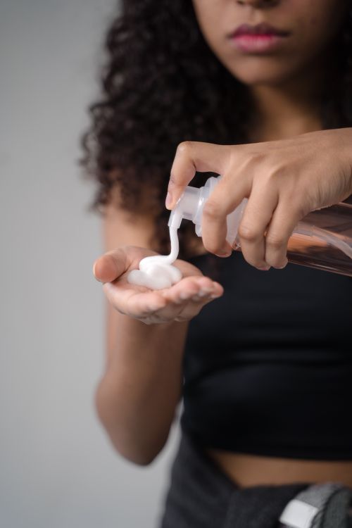 Free Close-up of a woman applying cream with a pump bottle, focusing on skincare and grooming. Stock Photo