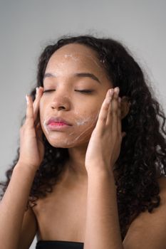 A serene moment of a young woman cleansing her face with facial wash in a skincare routine.