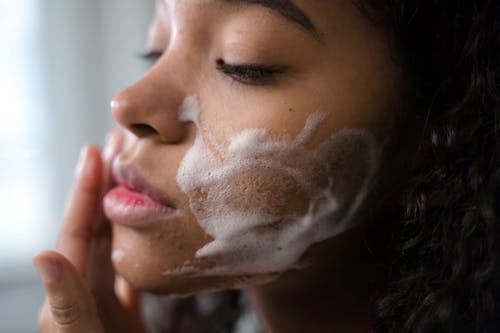 Free Close-Up Shot of a Curly-Haired Woman Cleaning Her Face Stock Photo