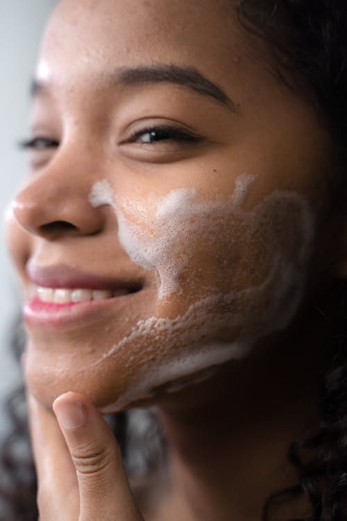 Free Close-Up Shot of a Curly-Haired Woman Cleaning Her Face Stock Photo