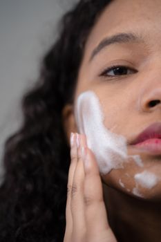 Close-up of a woman applying facial skincare product, promoting self-care routine.