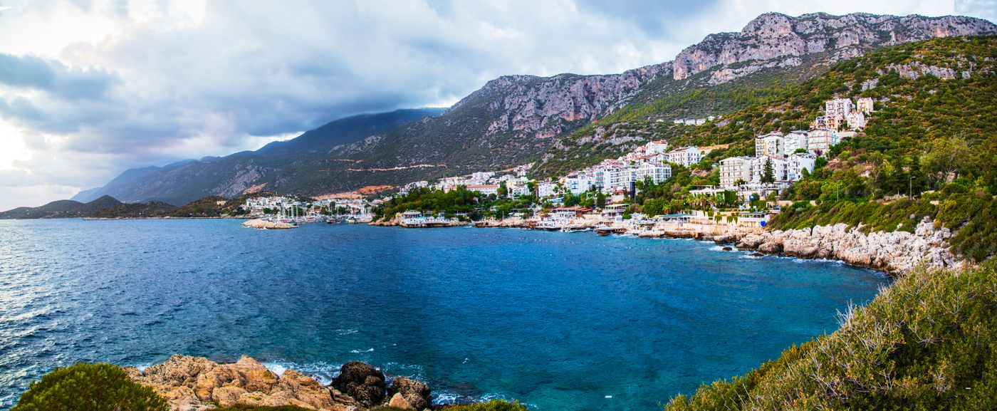 Mediterranean coastal town with mountain backdrop above a calm harbour