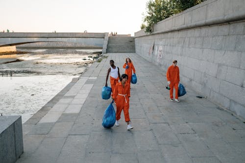 Group of People Carrying Trash in Plastic Bags