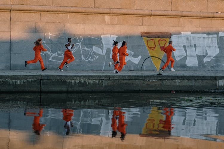 Inmates Running By A Wall With Graffiti