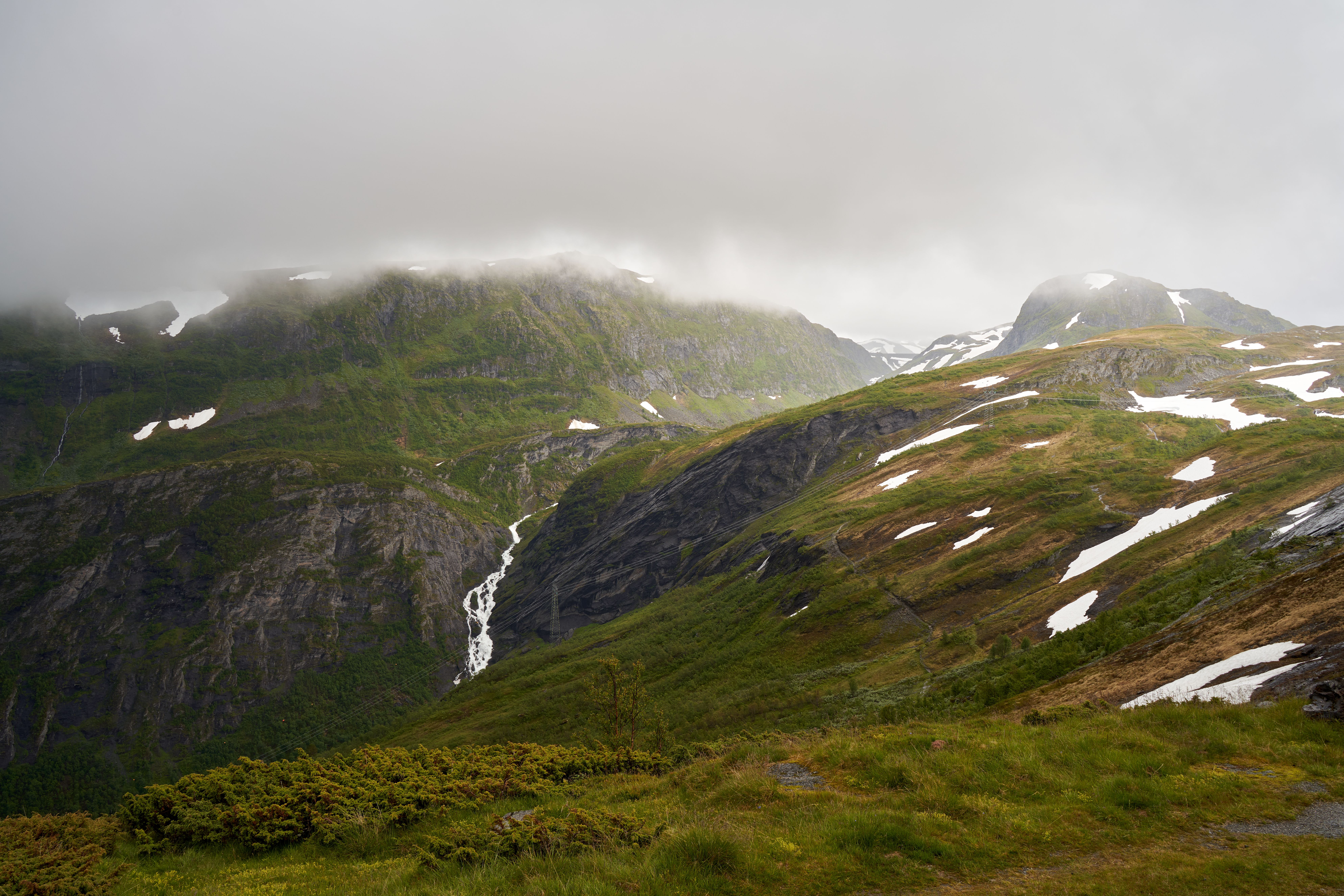Amazing All-inclusive Northern Lights Hunt Review: An Unforgettable Norway Expedition Review 2026 - A mist-covered mountain landscape featuring a cascading waterfall and lush greenery.