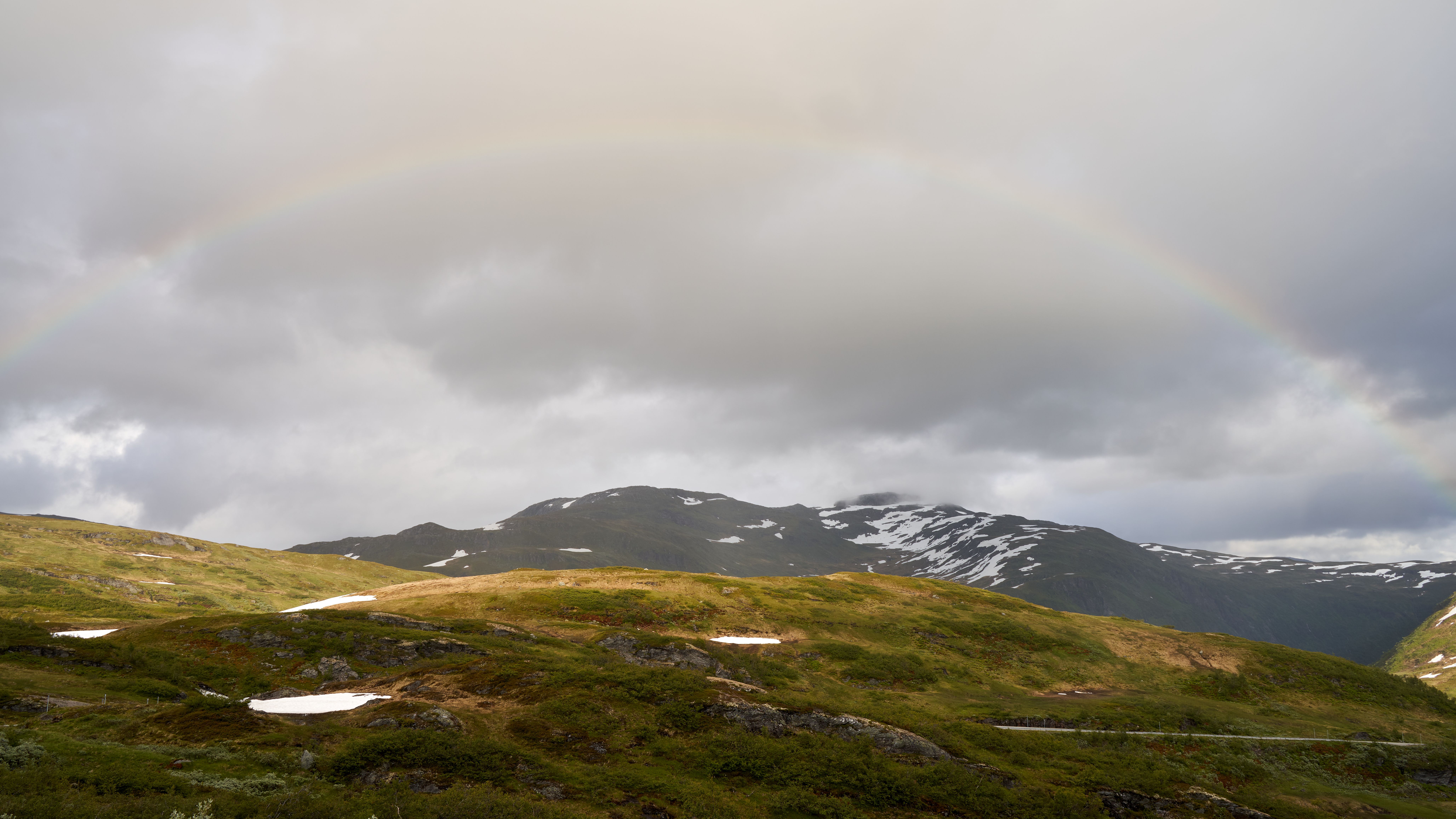 Beautiful mountain landscape with rainbow and cloudy sky